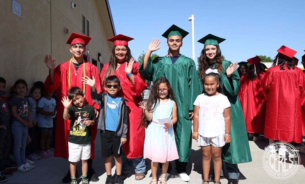 Graduating seniors in caps and gownswith elementary students