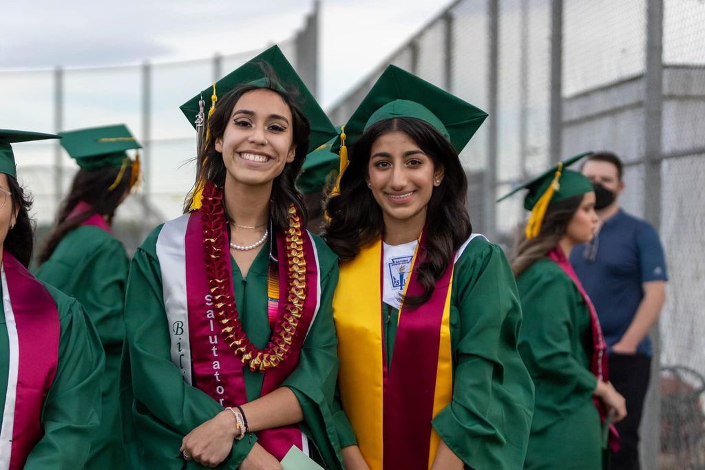 Two female students wearing grad cap and gown.