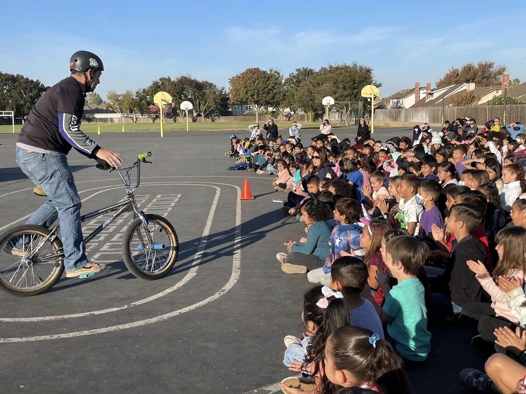 BMX rider talking with students outside on basketball court