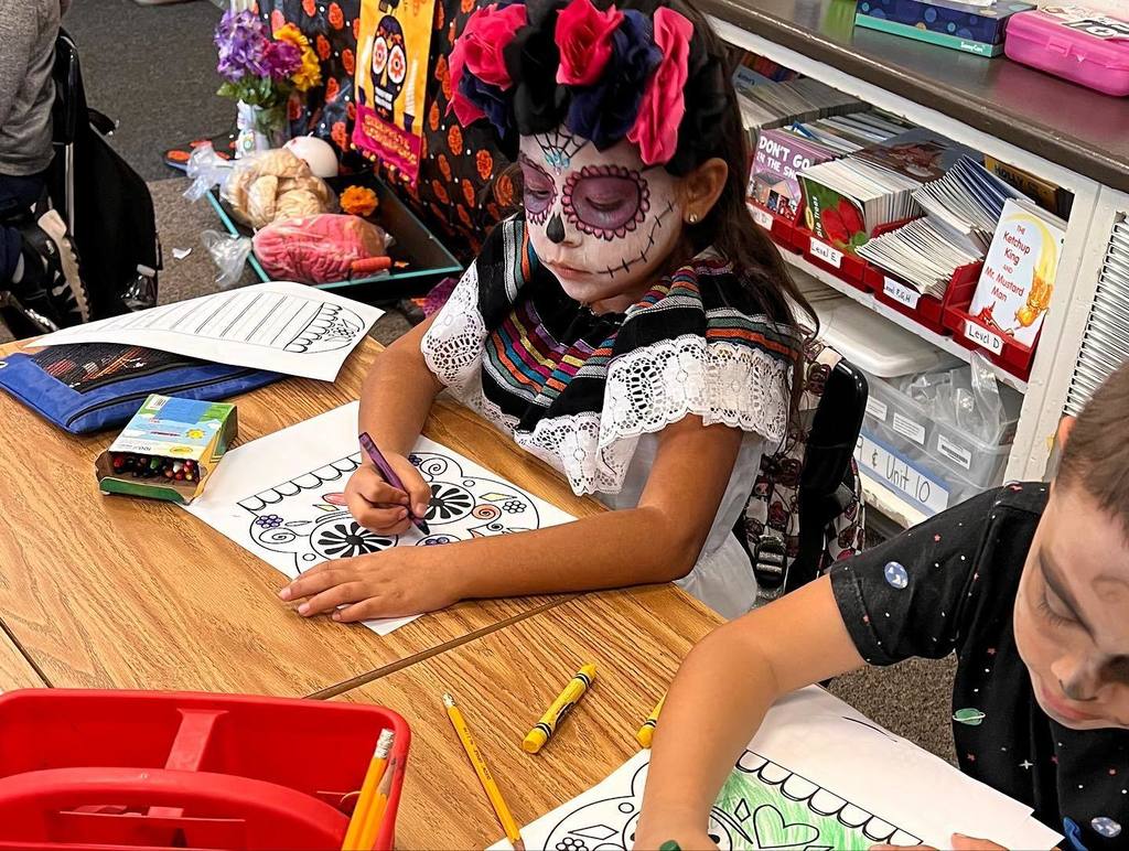 child with face paint coloring at desk