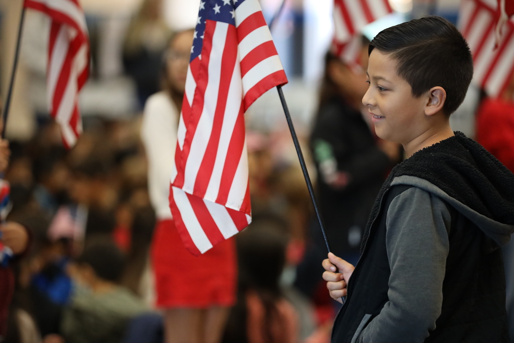 Young male student waves U.S. flag at veteran tribute