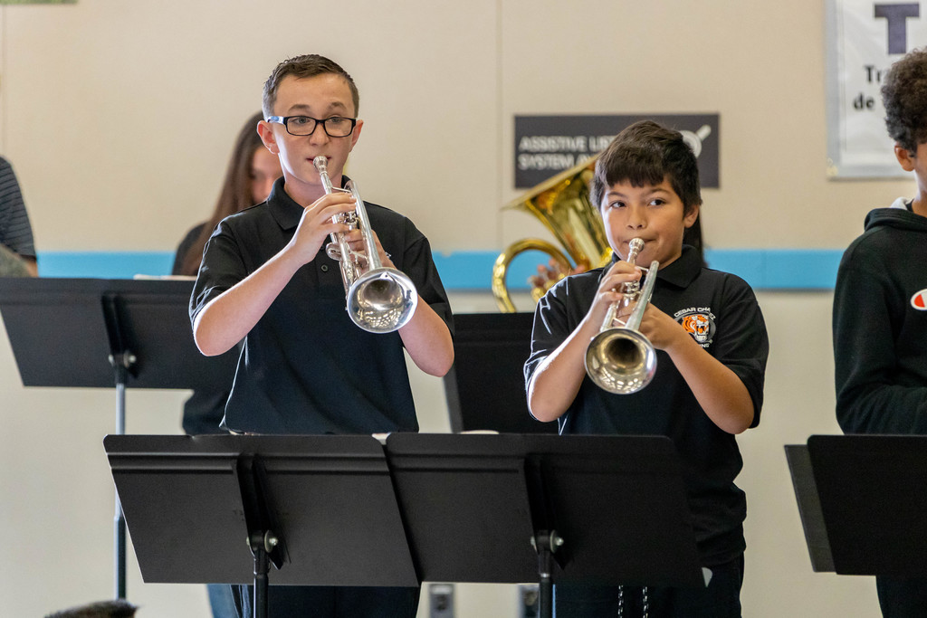 Two male junior high students dressed in black playing trumpets
