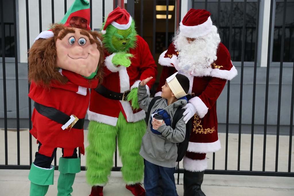 Young boy waves at the Grinch who is standing with Santa and a holiday gnome