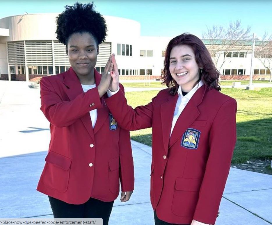 Two Central Valley High School students in burgundy jackets high-five one another