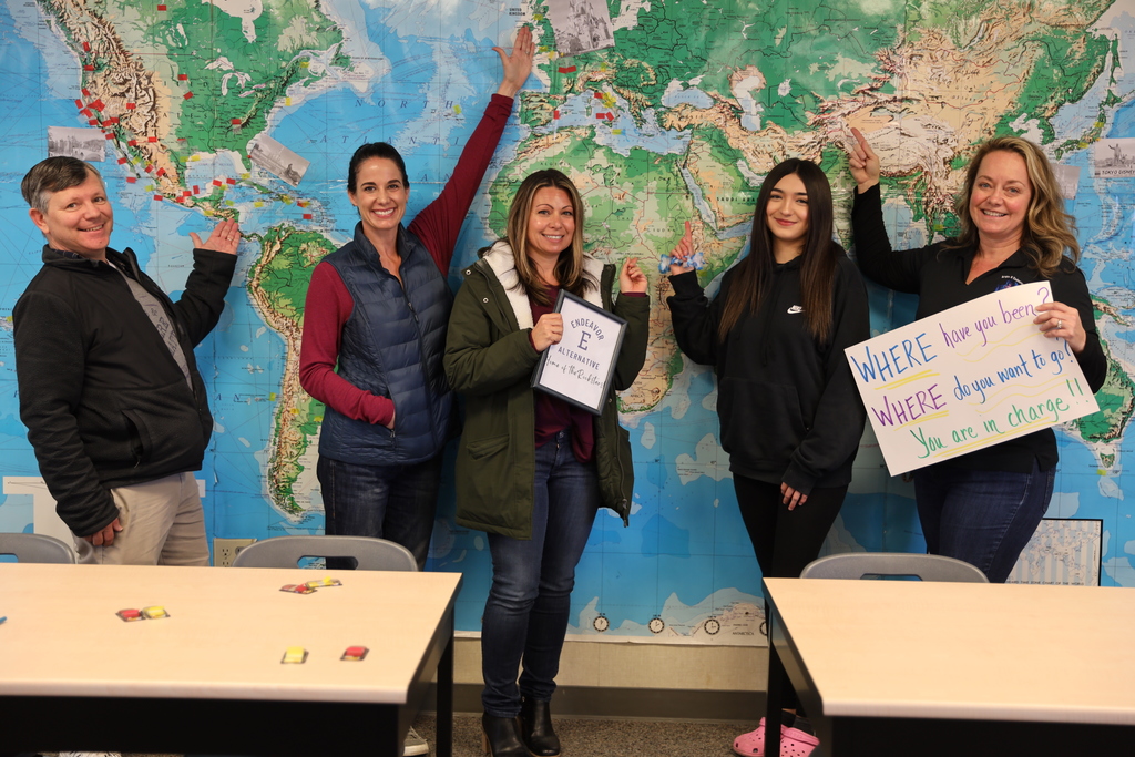 Students and staff in front of a wall-sized world map