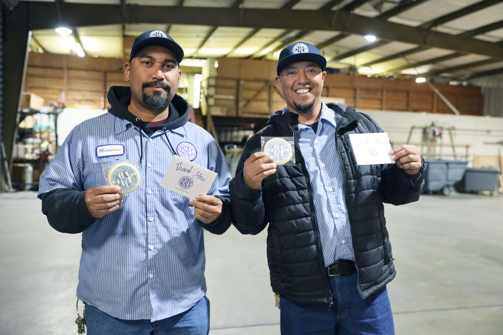 Two male Maintenance employees holding up cookies and thank you notes