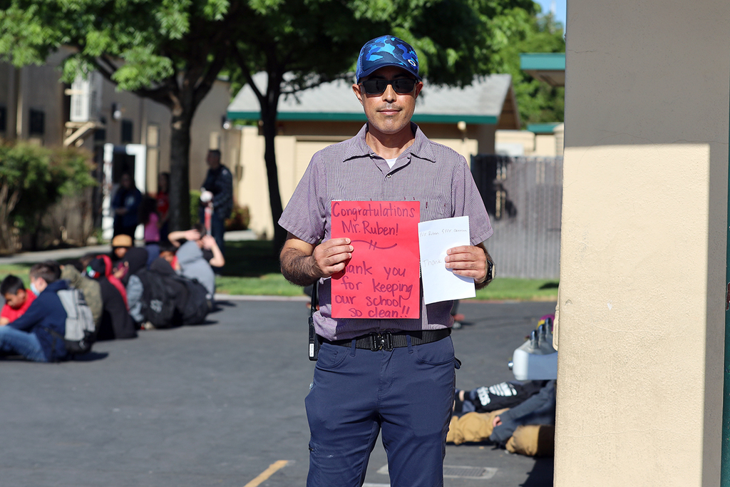 Mr. Ruben holds a red sign made by students