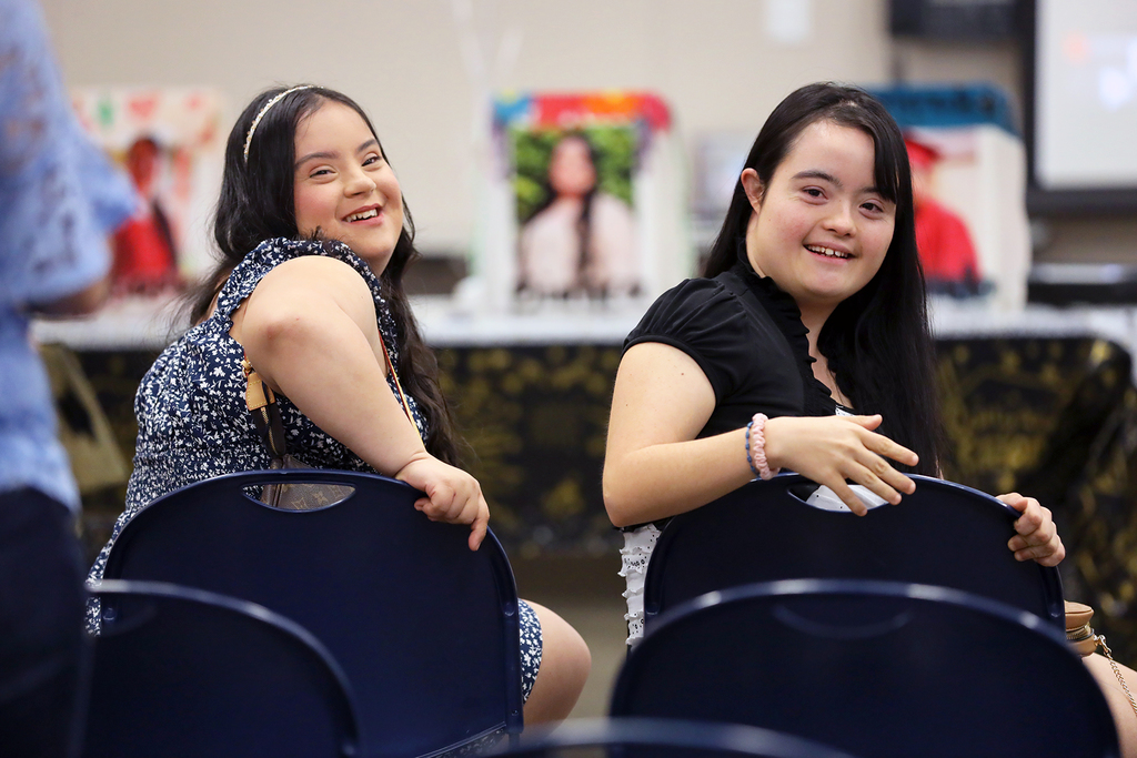 Two smiling girls face backwards in chairs