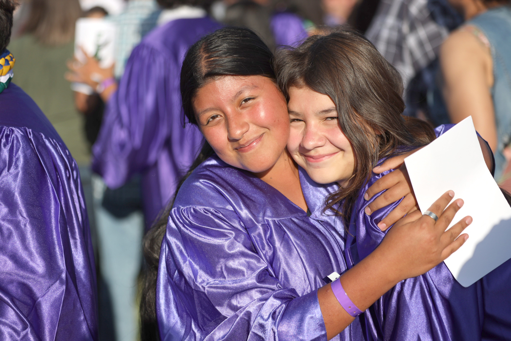 Two female Blaker-Kinser Junior High students in purple gowns exchange hug