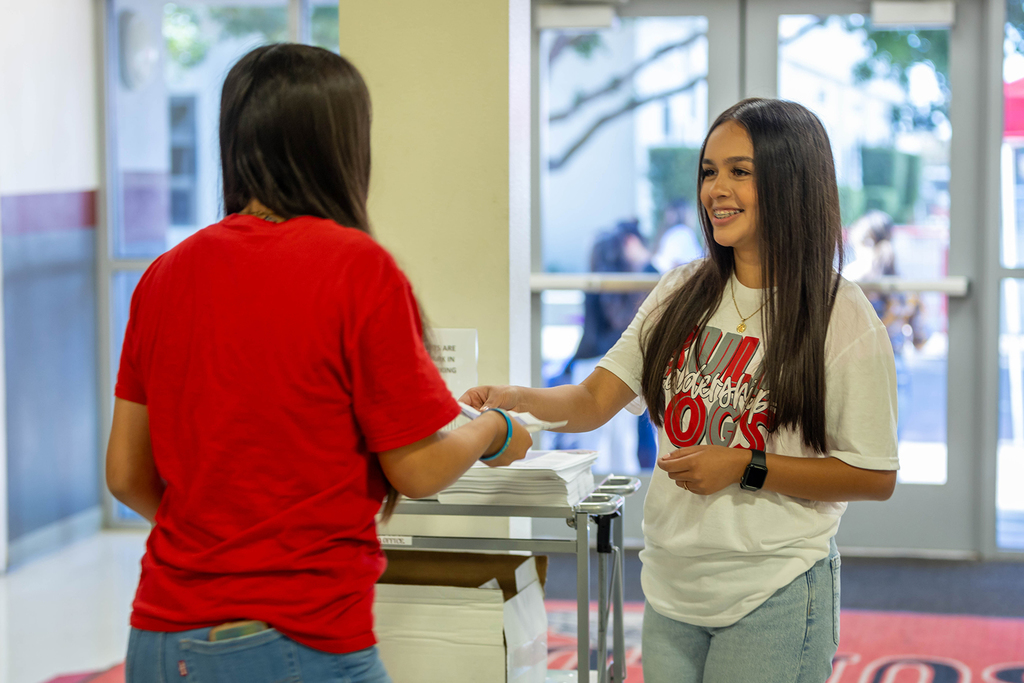 Student receives document from staff member