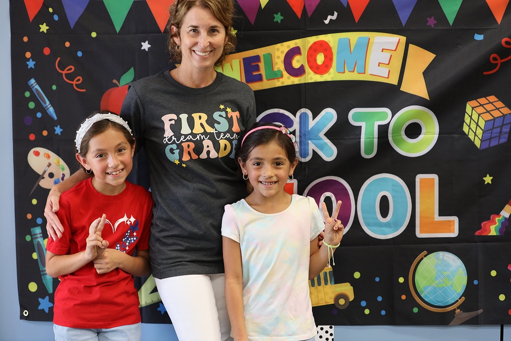 Teacher and two students in front of back to school sign